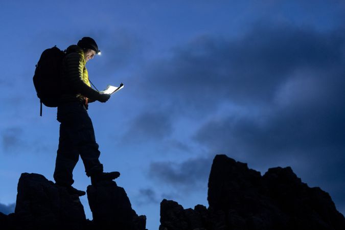 Man in yellow jacket walking on rock formation during nighttime