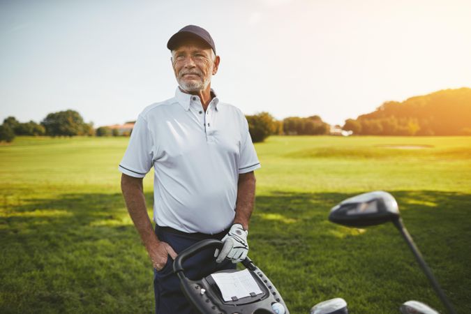 Man standing on golf course with clubs