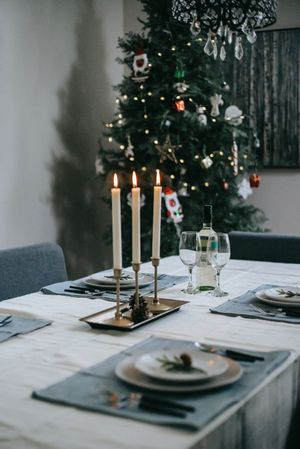 Dinner set-up with candles beside Christmas tree
