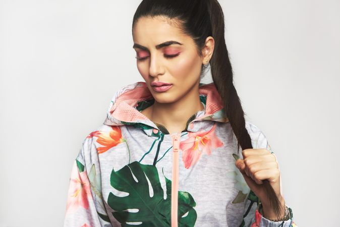 Beautiful woman in ponytail pictured in colorful printed floral hoodie with her eyes closed