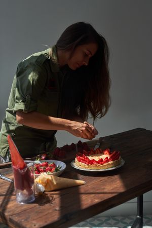 Cheerful woman decorating cake on table
