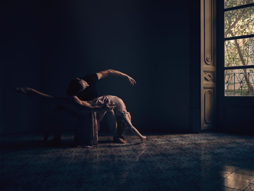 Graceful ballet dancers in dark ball room