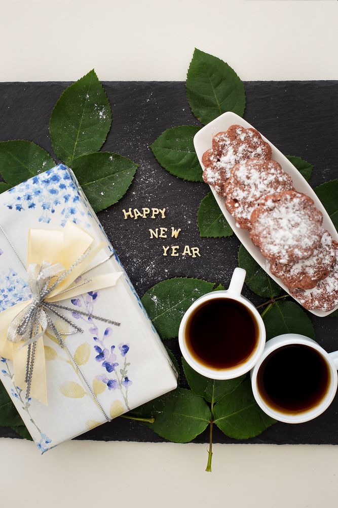 inscription of new year on a board with gift, muffins and coffee
