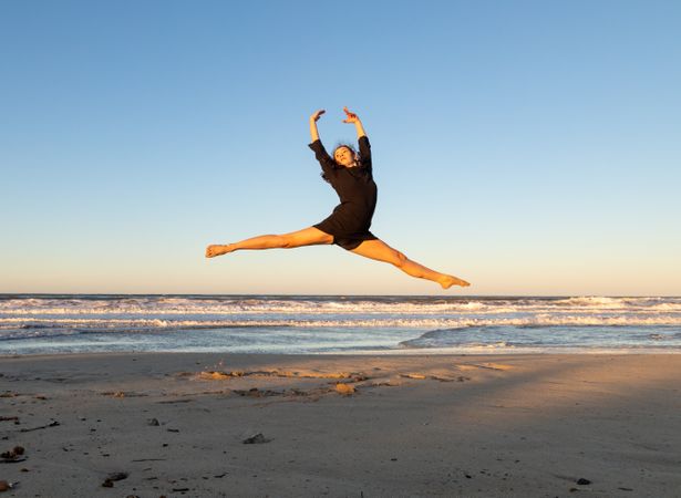 Woman jumping near water on shore