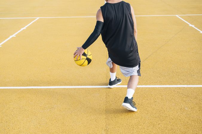 crop Young man and ball playing on basketball court outdoor.