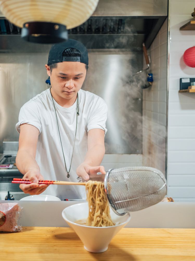 Asian male cooking ramen in cafe