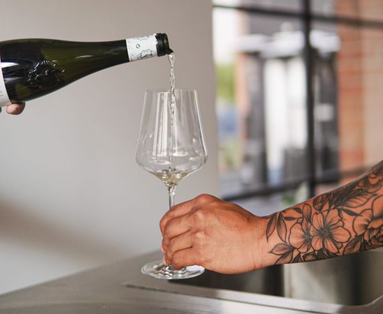 Cropped image of tattoo hand holding a glass of wine