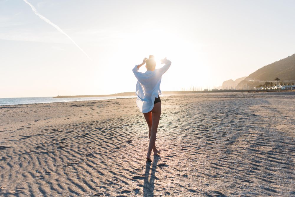 Woman walking along beach at dusk