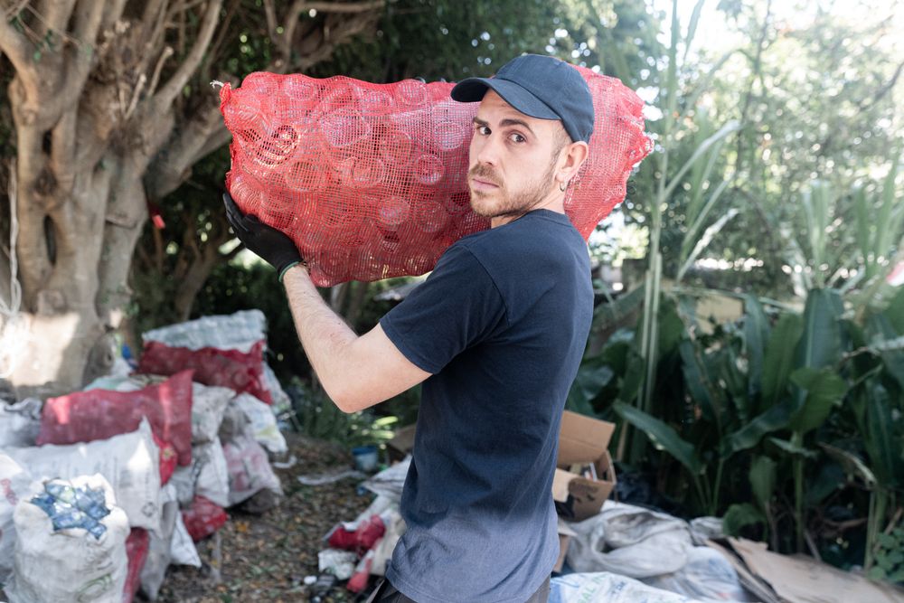 Young Man Handling Glass Recycled Bottles at Recycling Facility. Serious attitude