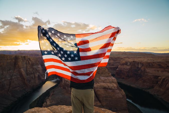 Anonymous male with USA flag near canyon