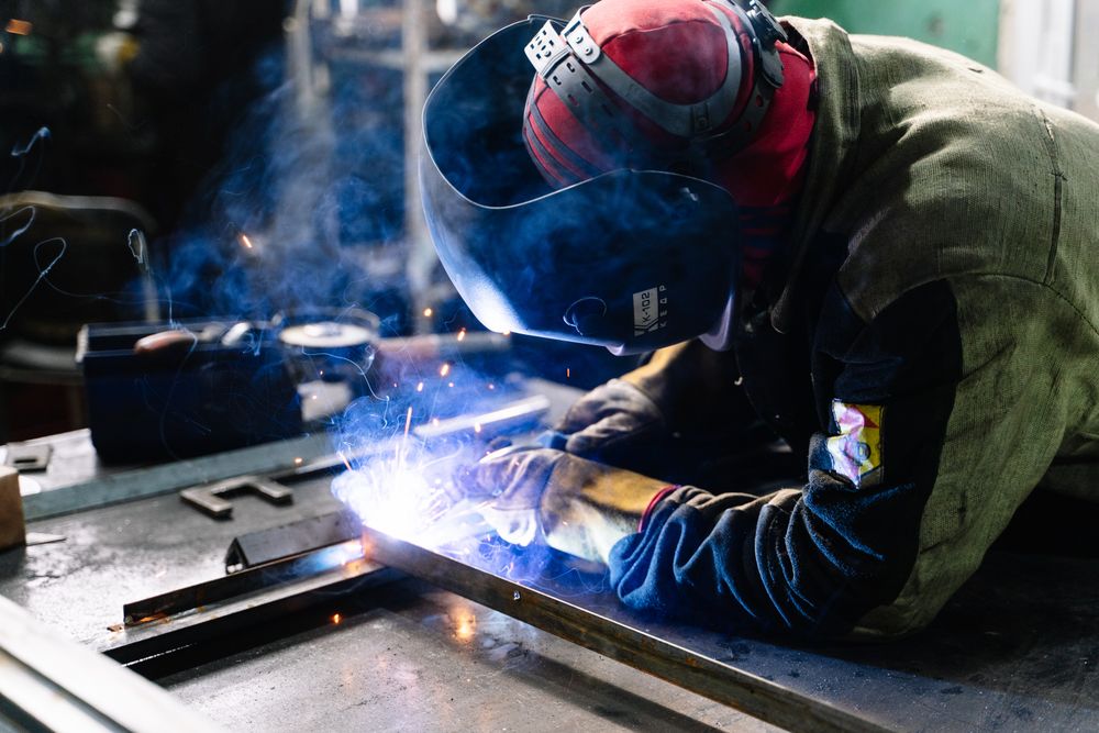 Side view of man in red helmet welding metal