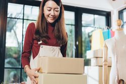Happy e-commerce business owner preparing orders in her studio