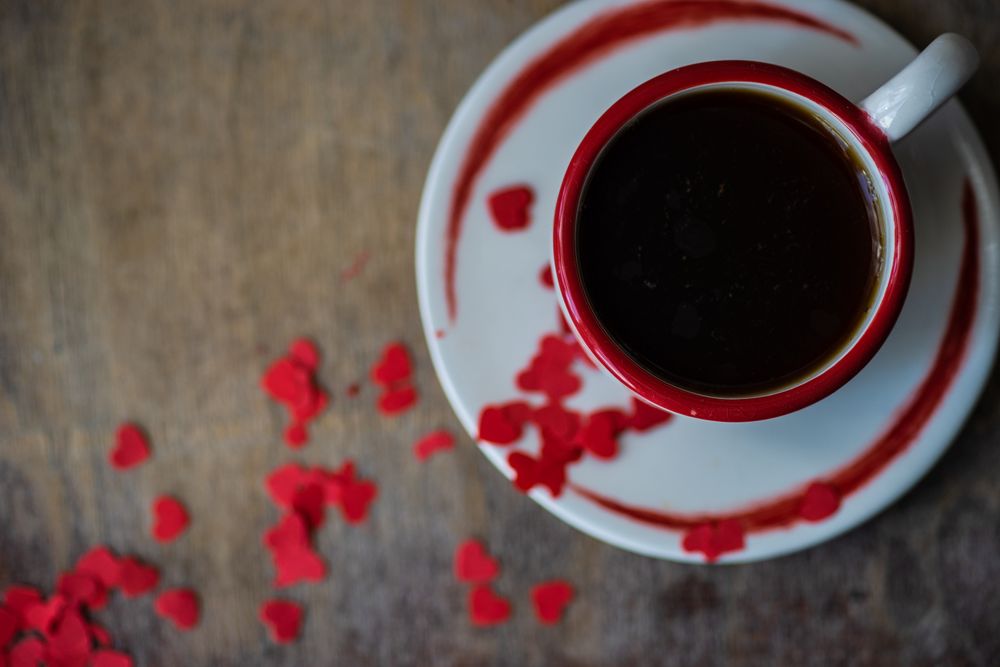 St. Valentine day card concept with top view of coffee with red heart confetti 