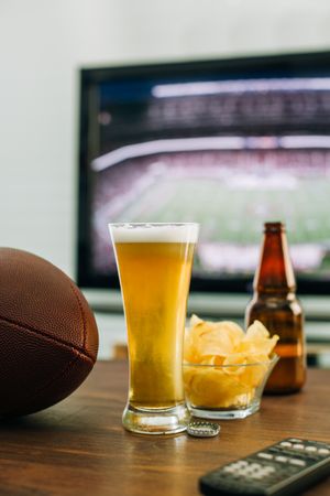 Beer and snacks prepared for watching american football on TV