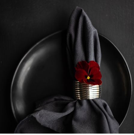 Top view of dark plate with napkin and red flower