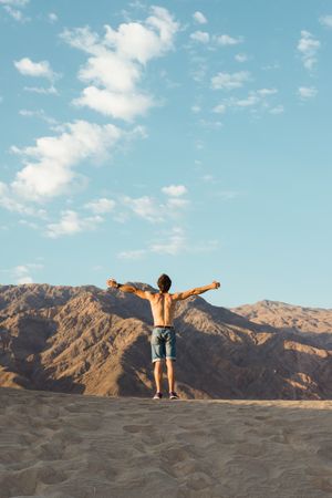 Back view of active young man without shirt enjoying wind in dry Death Valley
