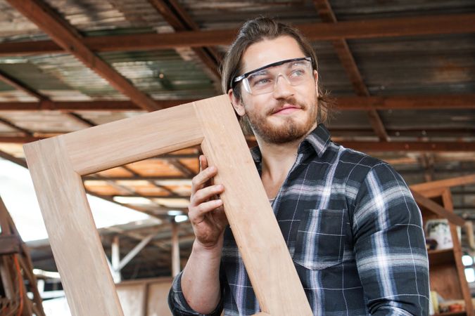 Male proud of a frame he made at his carpentry studio