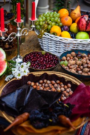 Bowl of fruit on celebratory bountiful table with nuts and candle