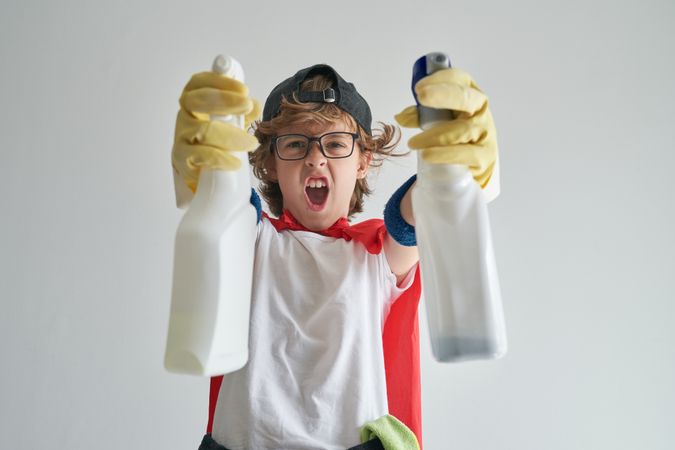 Excited boy with cleaner supplies standing in studio