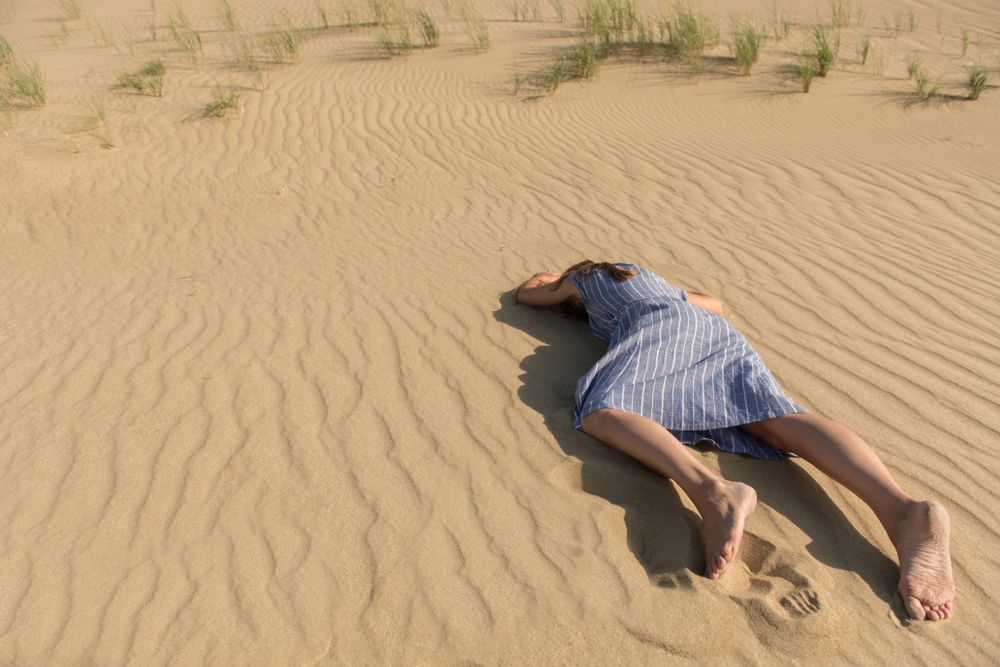 Young woman lying down on sand dune