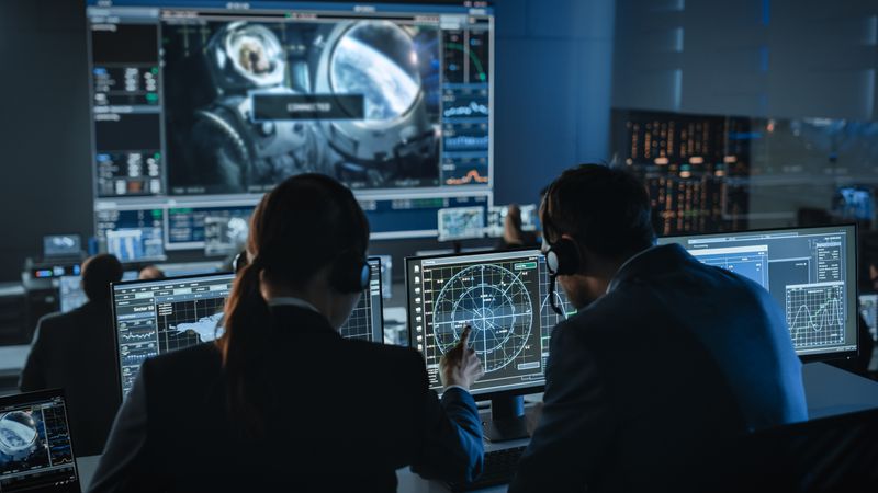 Mission Control Team Monitors Space Operation. Specialists Analyze Data on Multiple Screens, Including Radar and Medical Imagery.