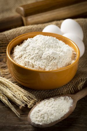 Bowl with wheat flour on the table.