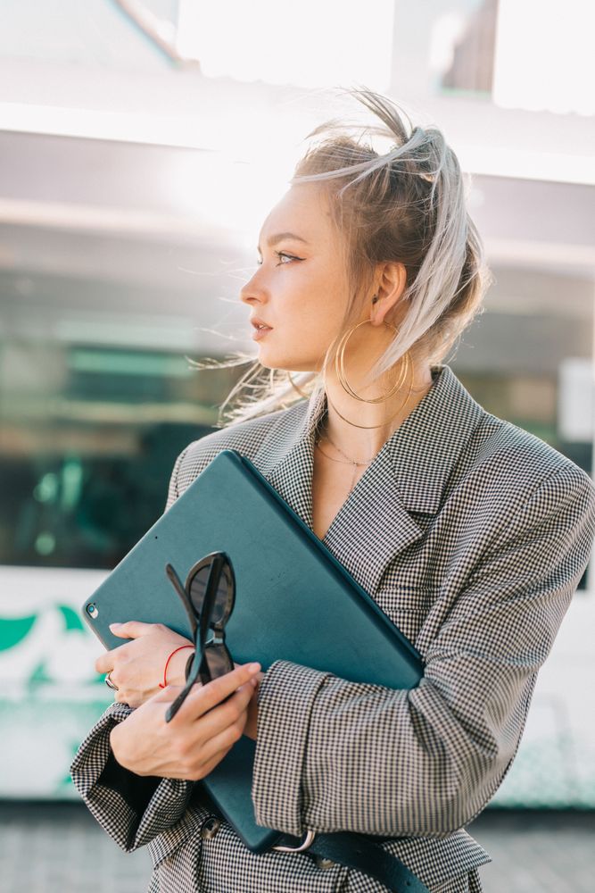 Thoughtful woman with ponytail hair holding tablet and waiting train