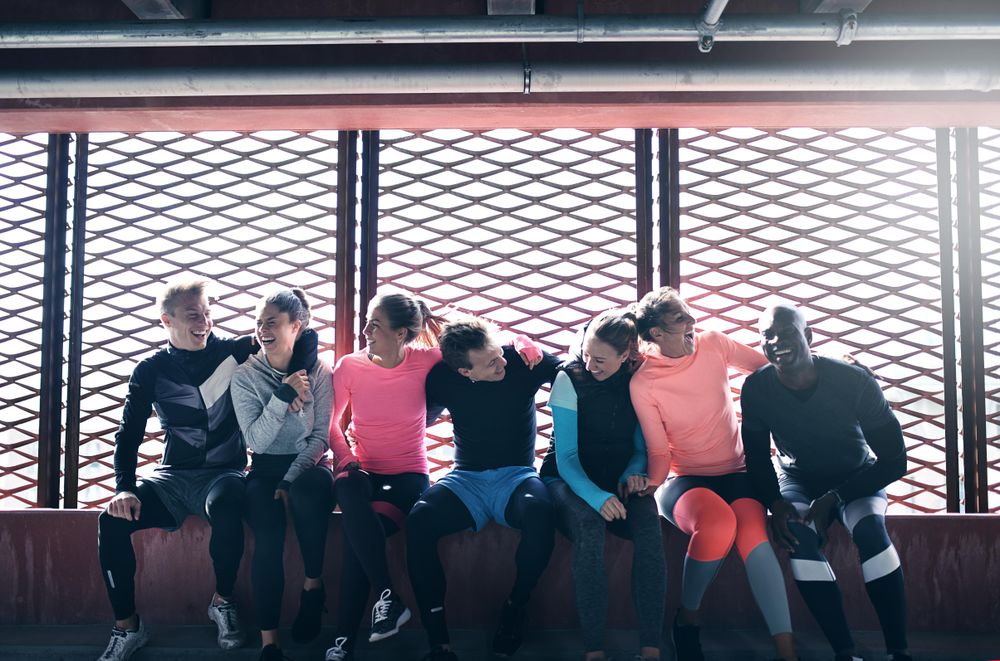 Multi-ethnic group of people in athletic gear sitting together and resting