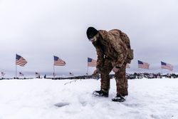 Nisswa, MN, USA - January 25th, 2020: A man ice fishing dressed in camouflage
