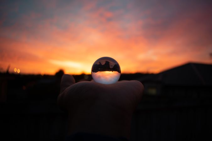 Person holding glass ball during sunset