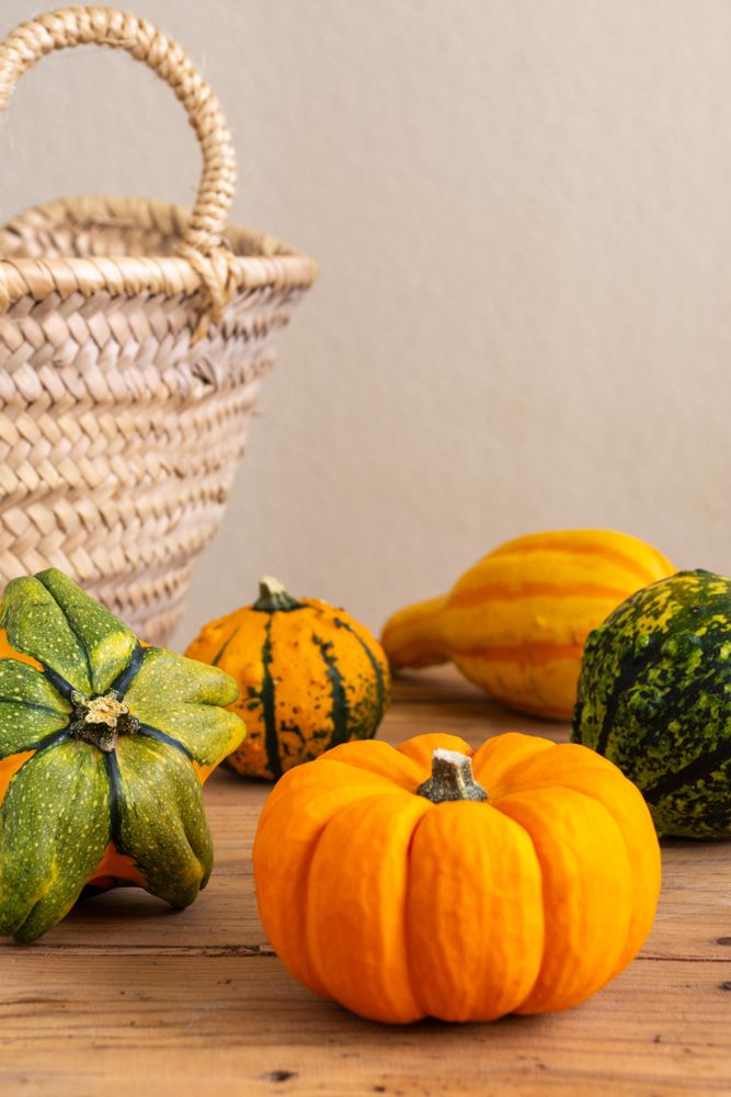 Pumpkins beside brown woven basket on wooden table
