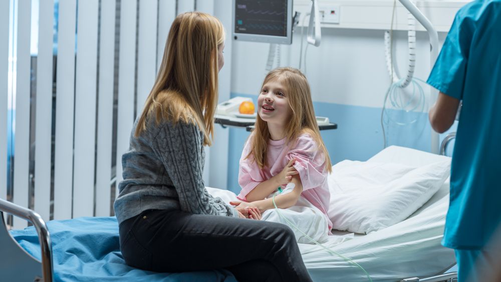 Healed Little Girl Sits on a Hospital Bed and Chats with Her Mother