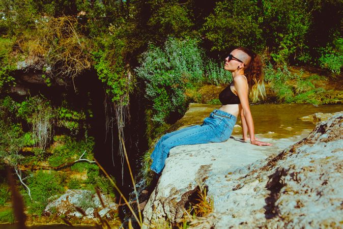 Young woman sitting near waterfall