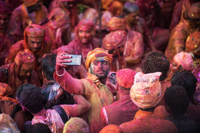 Man in crowd taking selfie during  Indian Holi festival