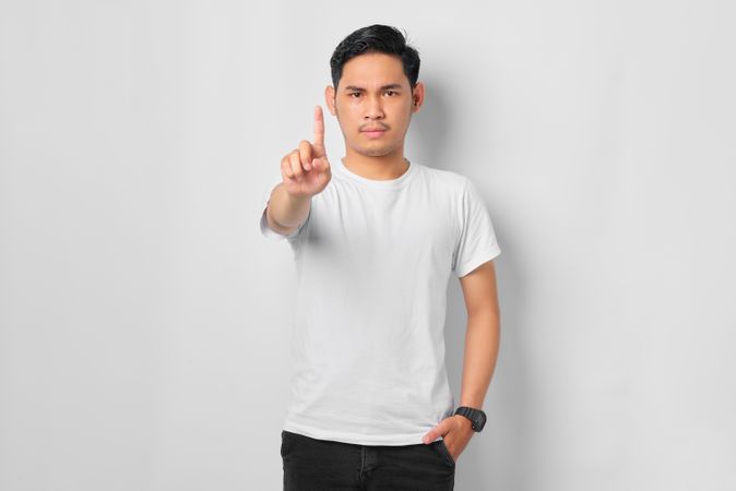 Asian male in grey studio pointing a finger up