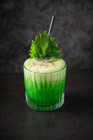 Delicious green cocktail garnished with foam shiso leaf and grat