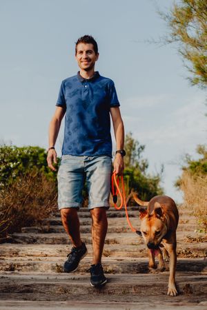 Happy adult man walking with dog along rural pathway