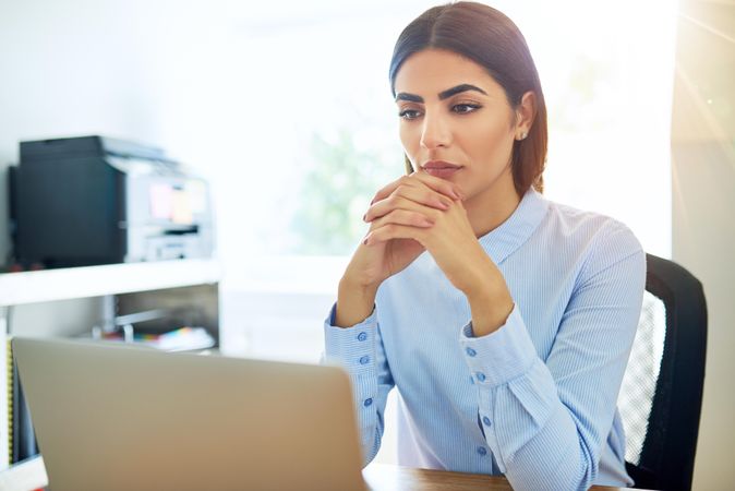 Woman looking somberly at computer while thinking about a problem