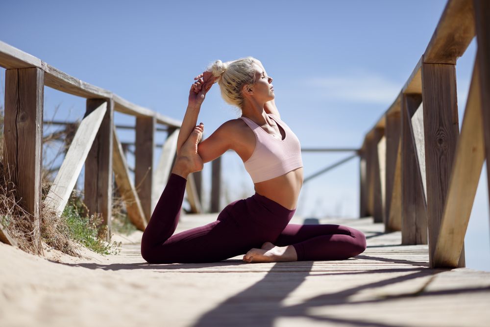 Woman doing relaxing stretches on a wooden beach walk way