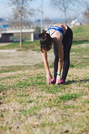 Woman bent over touching toes in park