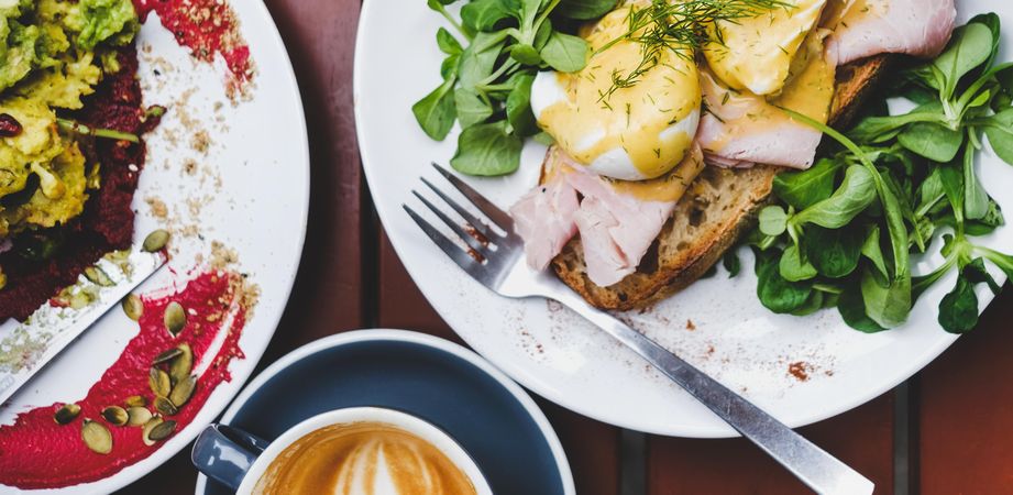 Eggs Benedict with greens, coffee, top view, wide composition