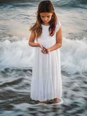 Smiling girl standing on seaside among waves