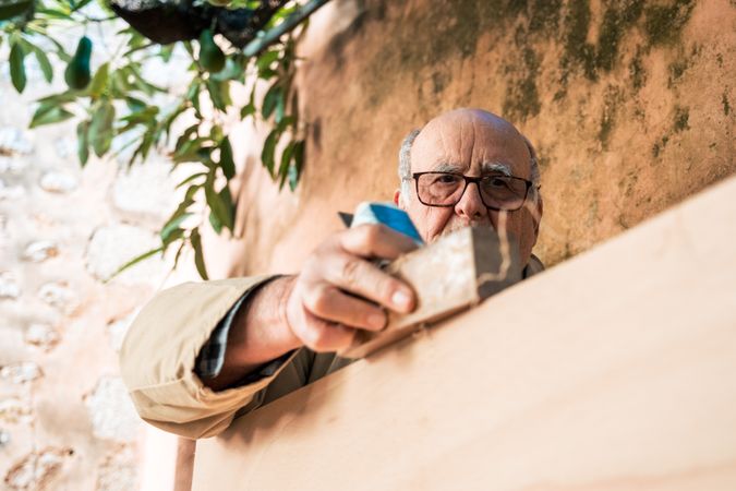 older man shaping wood with plane tool