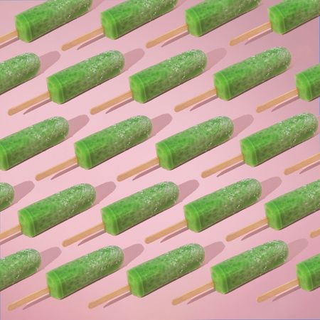 Rows of green ice pop on pink background with shadow