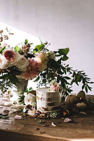 plate with cake decorated flower on table with bouquet of blooms in vase
