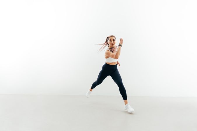 Sporty woman running forward indoors