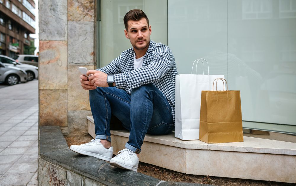 Young man with shopping bags sitting