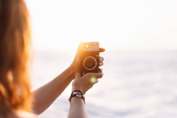 Creative woman taking photo on camera in sunny day