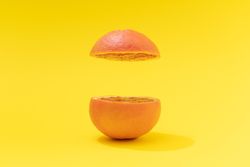 Sliced red grapefruit on bright yellow background