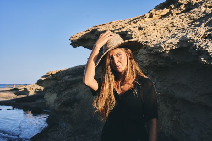 Cheerful woman holding hat in air